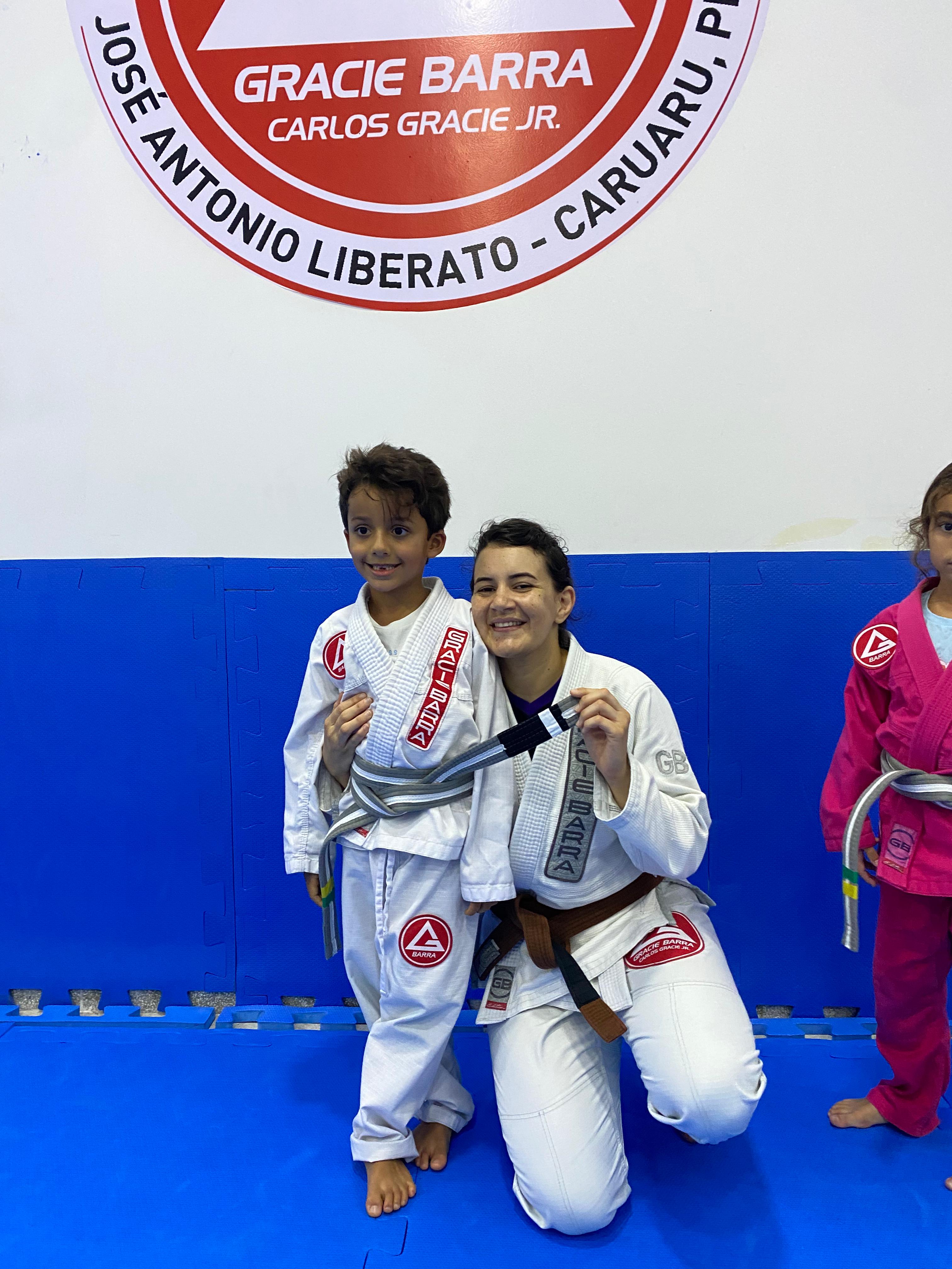 Karyne com aluno infantil recebendo graduação — logo GB Caruaru ao fundo