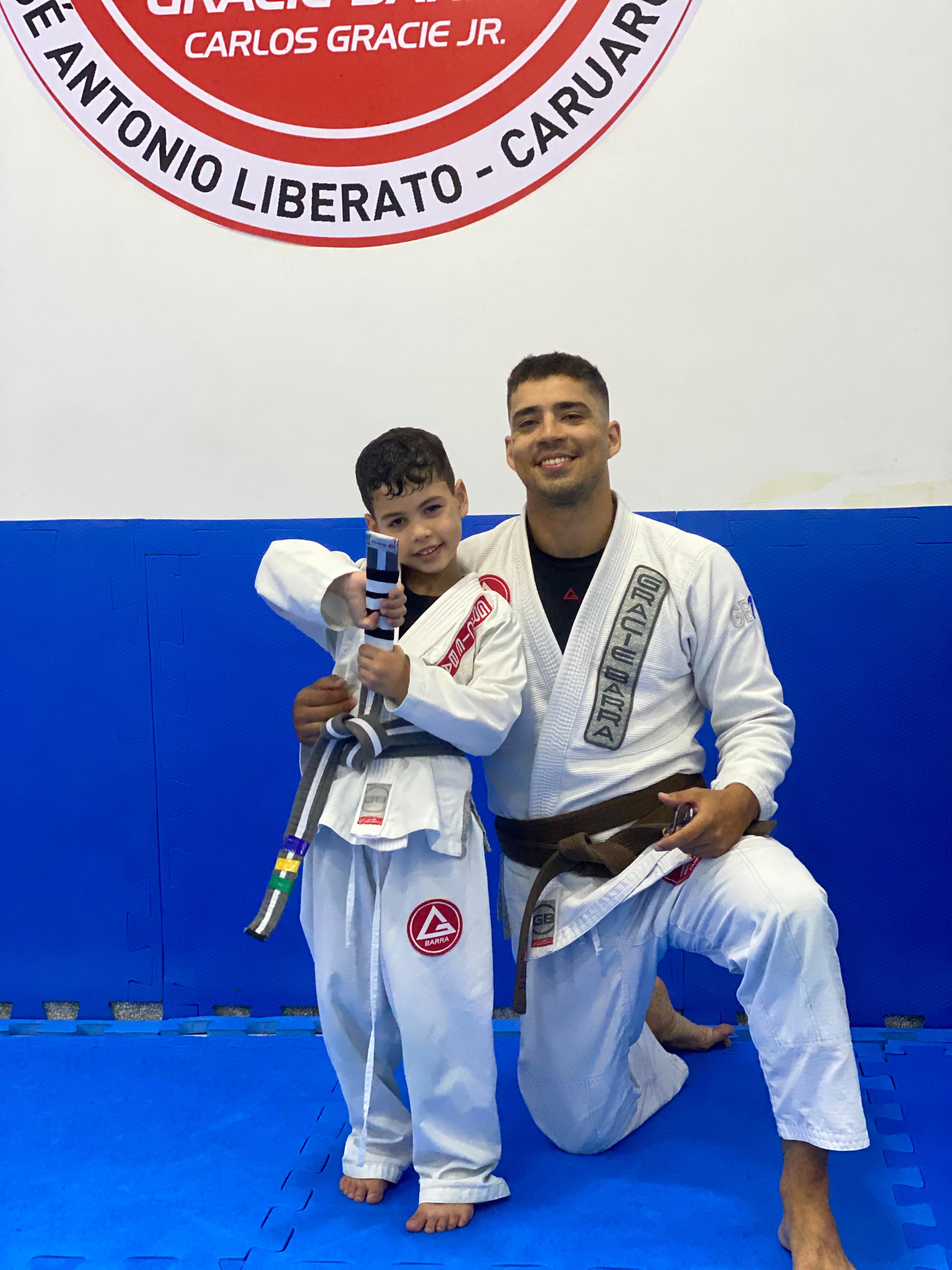 Professor com aluno infantil após graduação, logo GB Caruaru ao fundo