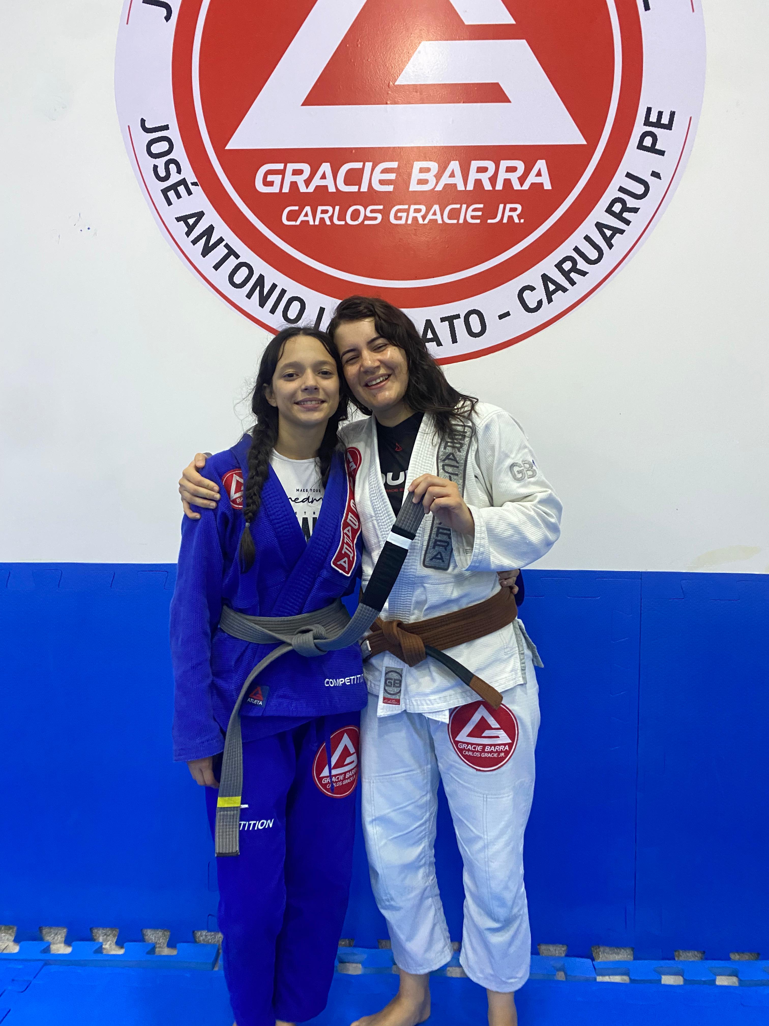 Karyne com aluna do programa feminino GBF em frente ao logo GB Caruaru