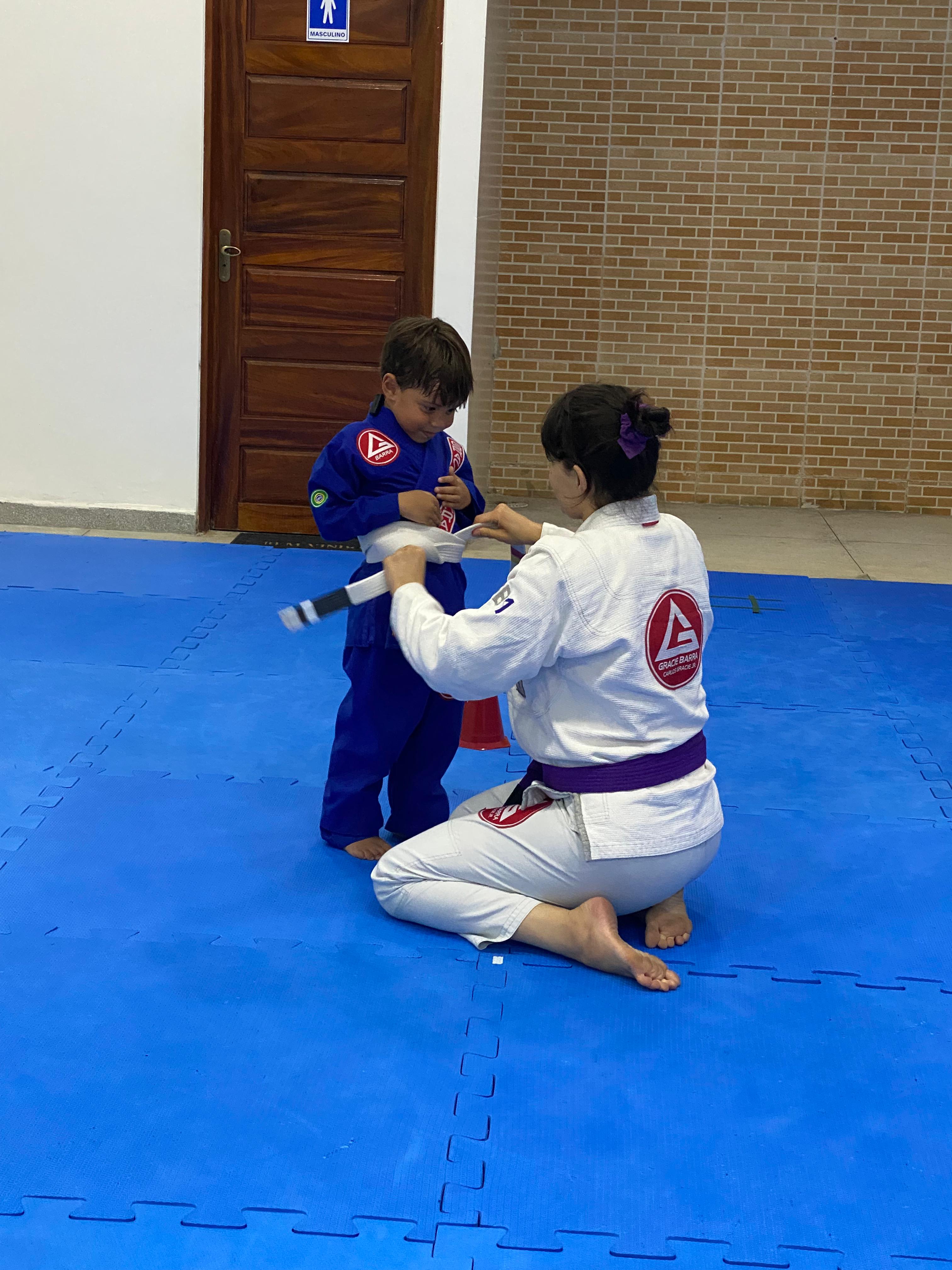 Professora faixa roxa trabalhando com aluno infantil no tatame
