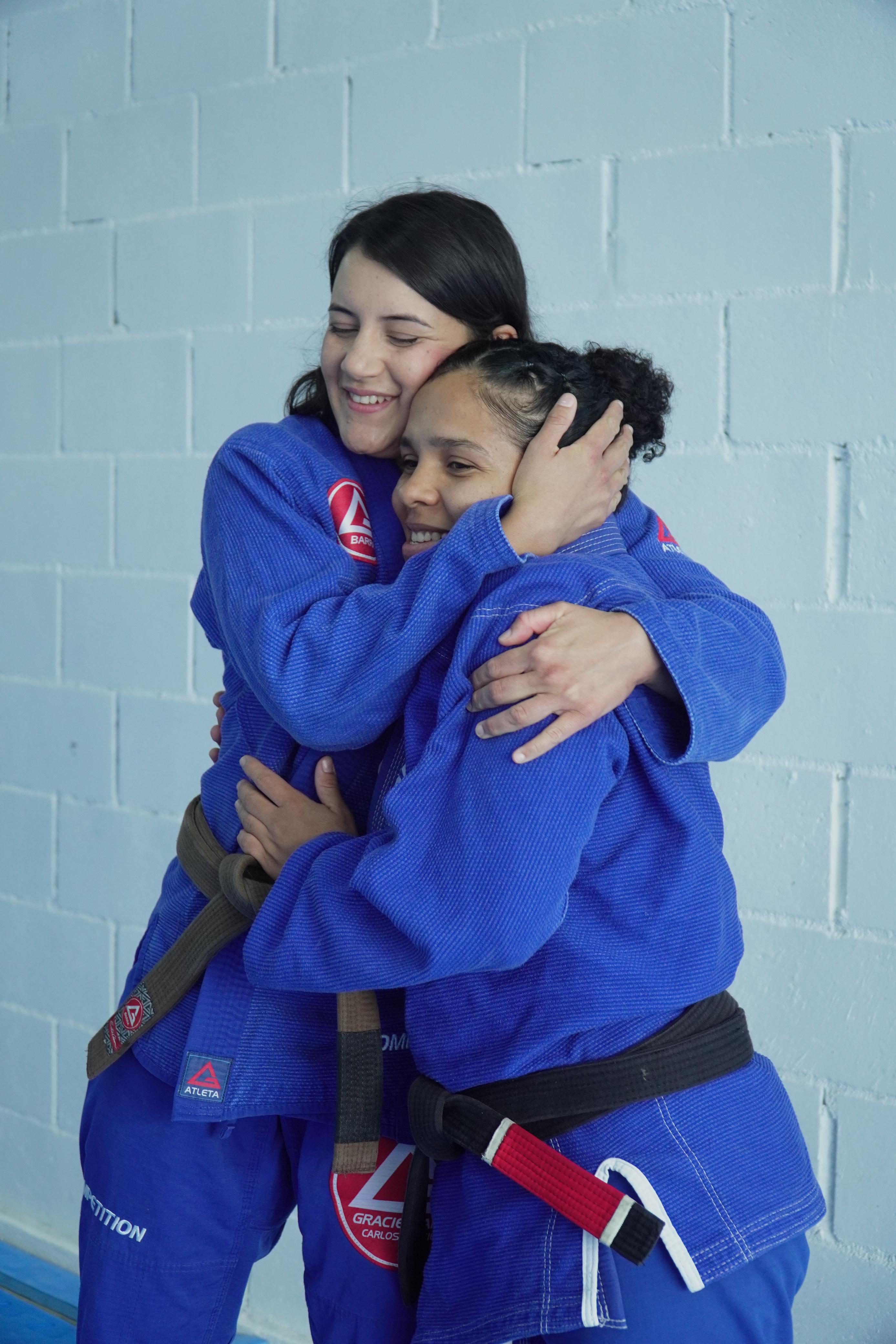 Duas alunas se abraçando de kimono azul Gracie Barra — amizade e companheirismo no tatame