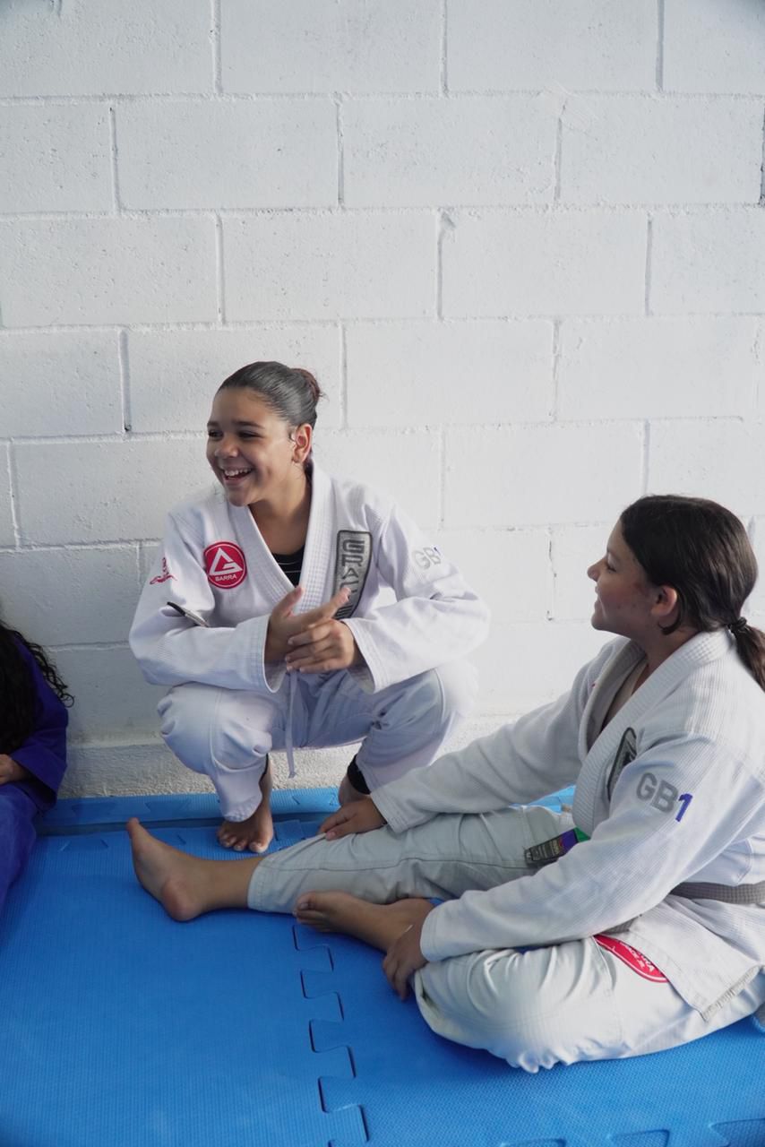 Alunas conversando e rindo no tatame da Gracie Barra Caruaru após o treino