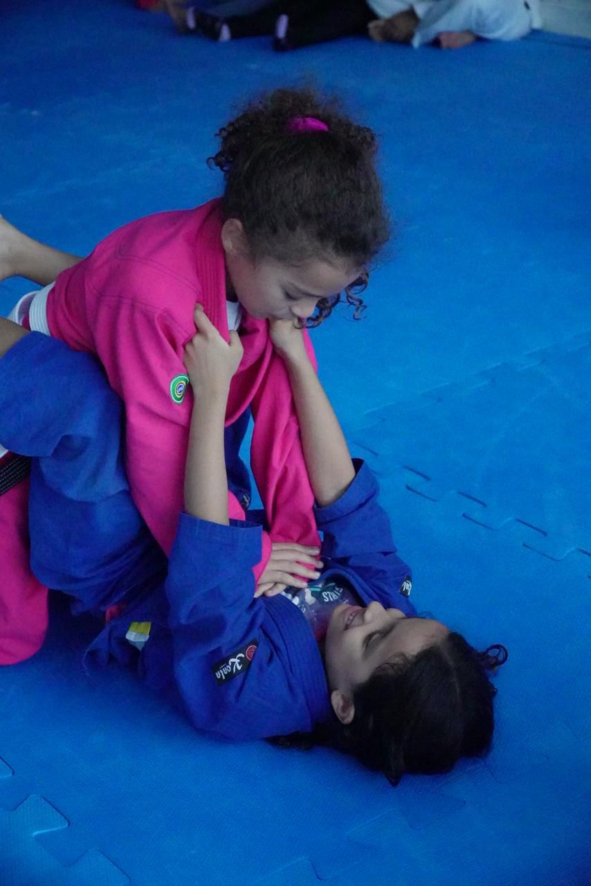 Menina de rosa em posição de guarda durante treino infantil na Gracie Barra Caruaru