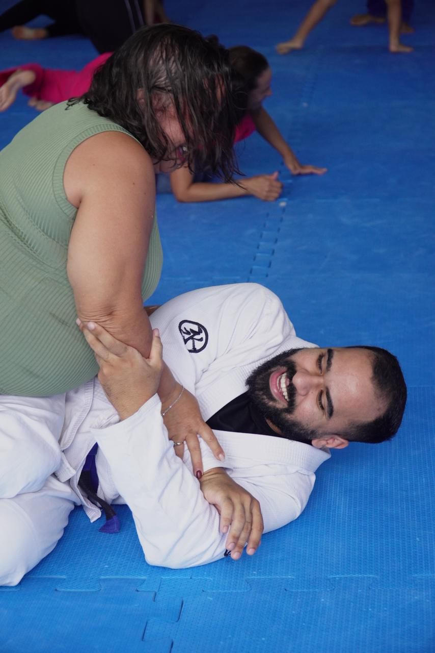 Aluna pratica técnica de defesa pessoal com professor faixa preta no tatame da GB Caruaru
