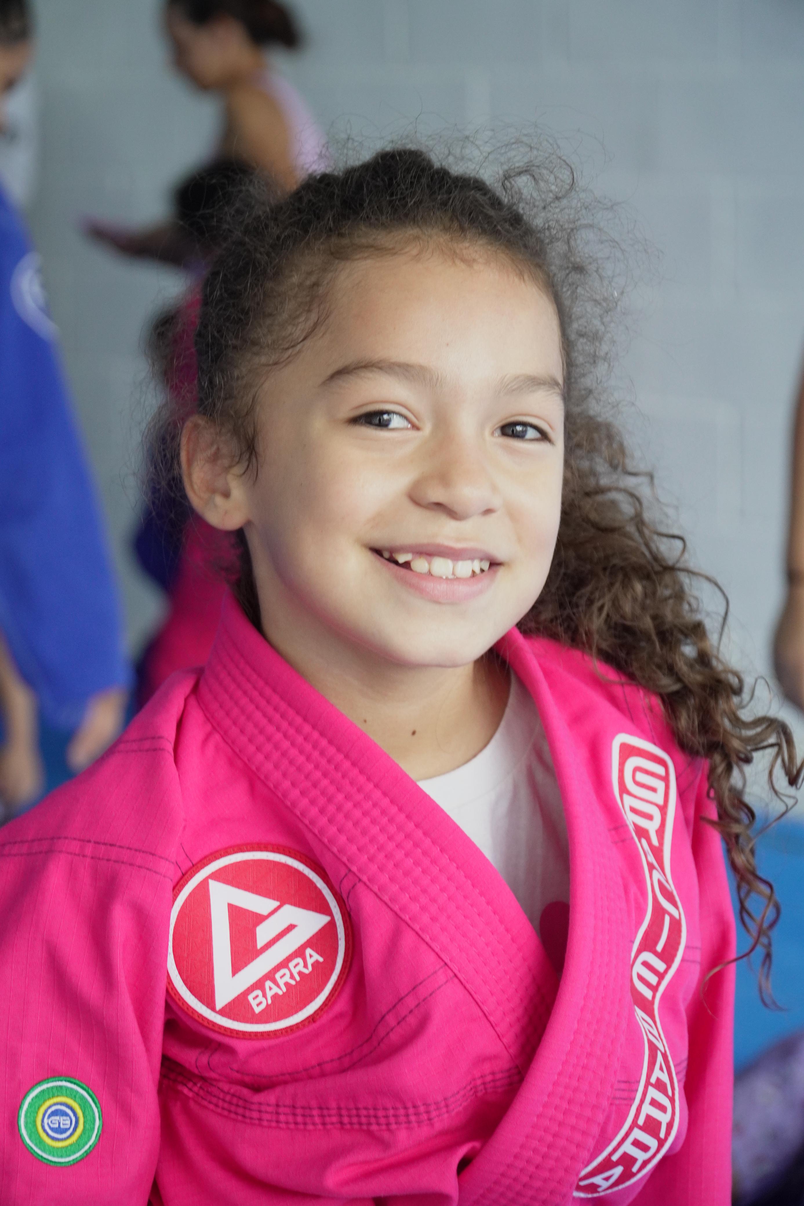 Menina sorrindo com kimono rosa da Gracie Barra — turma Pequenos Campeões Caruaru